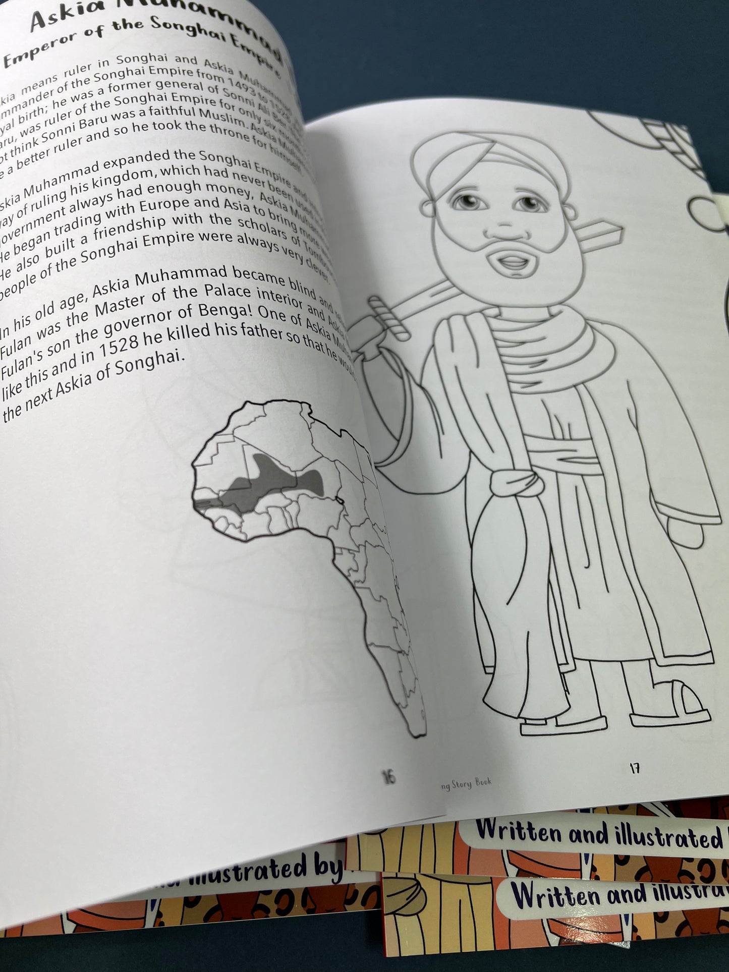 Open book with a coloring page of a historical figure and text on a dark surface.